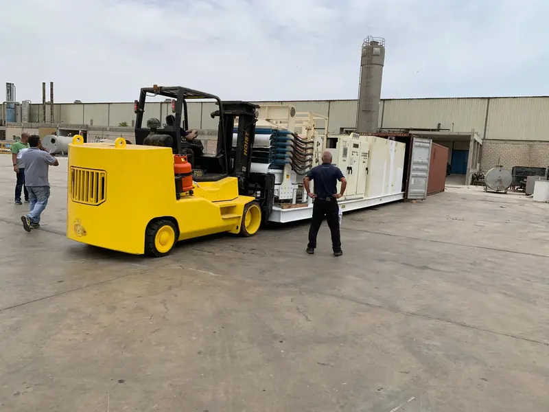Forklift loading factory equipment into containers